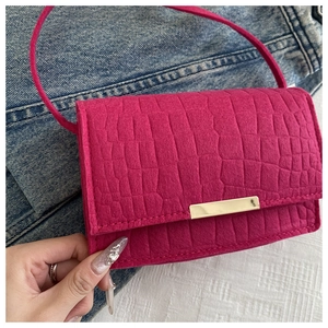 Close-up of rose red crocodile embossed leather handbag with golden metal bar decoration