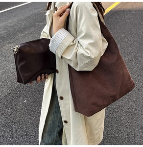 Detail of dark brown matte tote bag and matching smooth clutch bag set with gold zipper