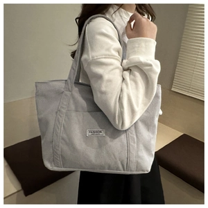 Detail of grey corduroy tote bag showing ribbed texture and fashion instinct label
