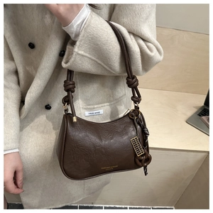 Detail of vintage brown leather handbag with knotted strap and gold abacus charm decoration
