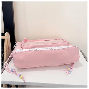 Detail of pink drawstring bag with white lace trim, PVC pocket and colorful beads