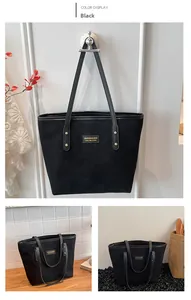 Detail view of large black tote bag featuring matte suede texture and metal logo plaque