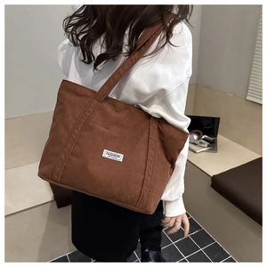 Close-up of brown corduroy tote bag featuring the FASHION INSTINCT woven label detail