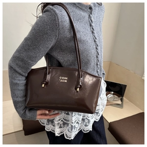 Detailed macro view of dark coffee patent leather shoulder bag with gold logo finish