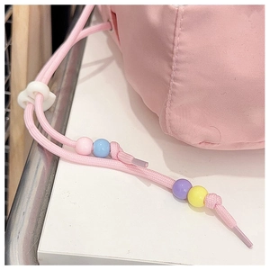 Detail of pink drawstring with macaron beads and white heart buckle on crossbody bag