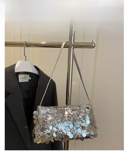 Detailed view of silver sequin square crossbody bag on a metallic display stand
