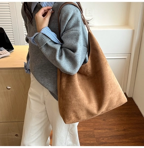 Close-up of brown suede tote bag with slim straps worn by a model in casual setting