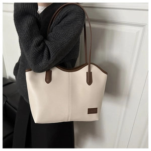 Detail of minimalist cream tote bag with dark brown straps shown on a model's shoulder