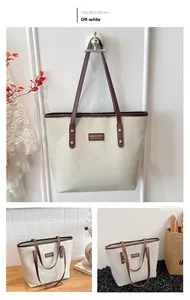 Detail of off-white tote bag featuring brown straps and a leather logo patch