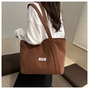 Detailed close-up of brown corduroy tote bag featuring a Fashion Instinct label