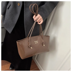 Detail of vintage brown leather handbag with gold logo and knotted handle design