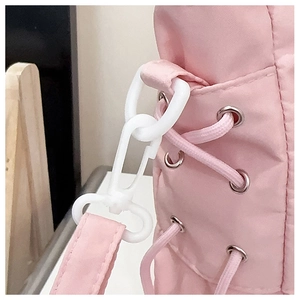 Close-up of pink crossbody bag side detail with white plastic hook and lacing detail