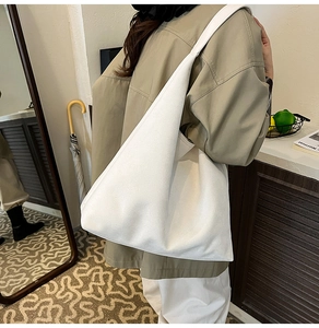 Detail showing high-capacity white matte leather tote bag worn as a shoulder bag