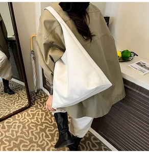 Minimalist white large triangle tote bag with deconstructed silhouette shown in lifestyle setting