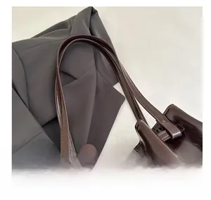 Detail of glossy deep brown patent leather tote bag with reinforced handles and stitching