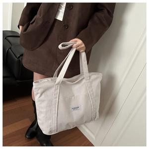 Close-up of cream corduroy tote bag showing vertical texture and Fashion Instinct label