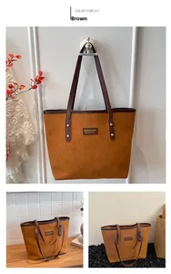 Detail of a large brown suede tote bag featuring dark leather handles and a gold logo plate