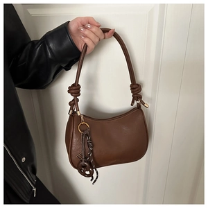 Detail of a brown crescent shoulder bag featuring a unique thick rope knot and metal clasp