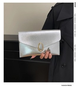 Detailed view of silver envelope clutch with textured finish and gold oval metal lock