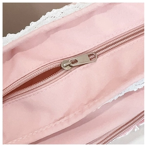 Detail shot of the pink crossbody bag featuring a silver zipper and white lace trim