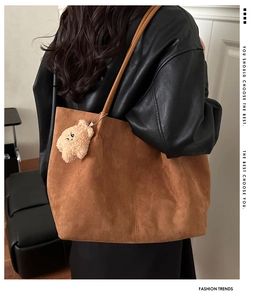 Détail d'un grand sac cabas en daim marron avec un joli petit ours en peluche jaune attaché