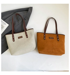 Close-up of matte suede tote bags in beige and caramel with rivet straps