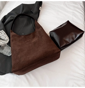 Detail of vintage brown suede tote bag and matching leather pouch on fabric background