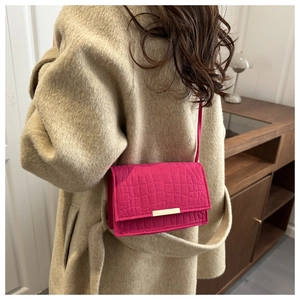 Close-up of fuchsia crocodile pattern leather bag with elegant gold metal buckle detail