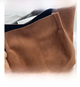 Détail du sac cabas en daim marron avec coutures renforcées et breloque en fourrure