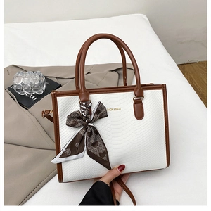 Detailed macro view of white snake-embossed leather tote bag with heart print scarf handle