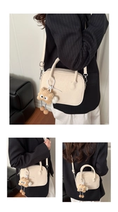 Detail of cream matte leather handbag with plush cartoon monster charm and adjustable strap