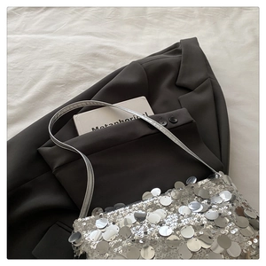 Detailed view of silver sequin shoulder bag on dark grey blazer fabric textures