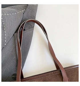 Detail of suede tote bag with brown leather handle and refined white contrast stitching