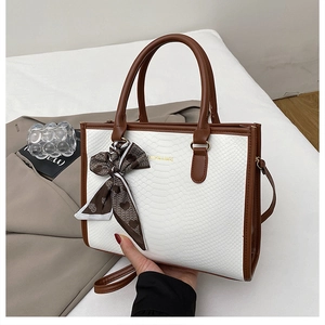 Détail du sac à main motif serpent avec garniture en cuir marron et foulard en soie cœur
