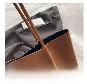 Détail du cabas en daim marron avec coutures fines sur un costume gris élégant