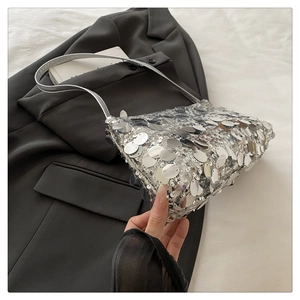 Close-up of large silver sequins on a trendy shoulder bag with leather strap details