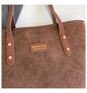 Macro detail of brown suede tote bag with golden rivets and logo leather patch