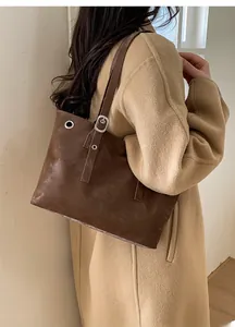 Dettaglio della borsa tote vintage in pelle marrone con rivetti e fibbie metalliche sulla tracolla