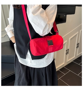 Detail of red cylindrical nylon shoulder bag with adjustable strap and buckle closure
