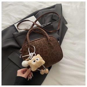 Detailed texture of dark brown leopard embossed handbag with a cute plush pendant