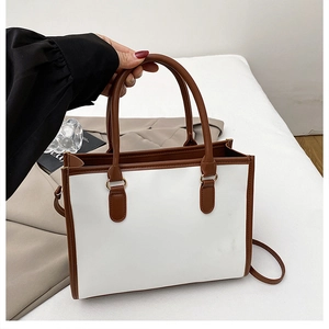Detail of the dual-tone tote bag featuring brown handles and gold hardware accents