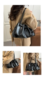 Detail view of black pleated oil wax leather tote bag with glossy finish on shoulder