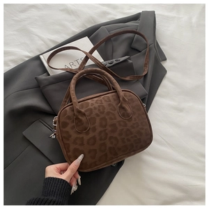 Detailed view of leopard print faux suede handbag with dual handles and metal hardware