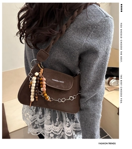 Detail of vintage brown matte leather flap bag with wooden beads and floral chain strap