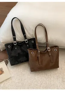 Close-up of black and brown tote bags showing metallic buckles and eyelet detailing