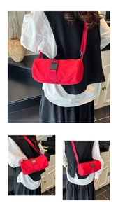 Detail view of a red cylindrical Oxford cloth crossbody bag with black plastic buckle strap