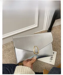 Detailed close-up of a silver envelope clutch bag featuring fine cross-grain texture and gold clasp
