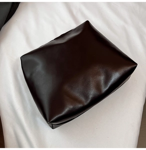 Close-up of vintage glossy dark leather tote showing premium texture and rectangular shape