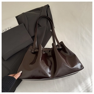 Detail of a dark coffee patent leather bucket bag featuring a unique pleated closure