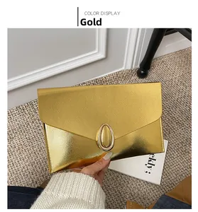 Detailed close-up of a golden envelope clutch bag with Saffiano texture and metal buckle